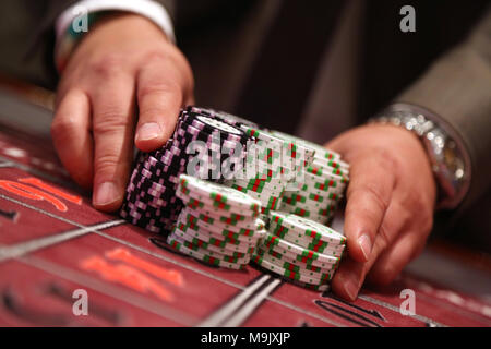 Giocatore al tavolo da gioco pusing grande pila di chip Foto Stock