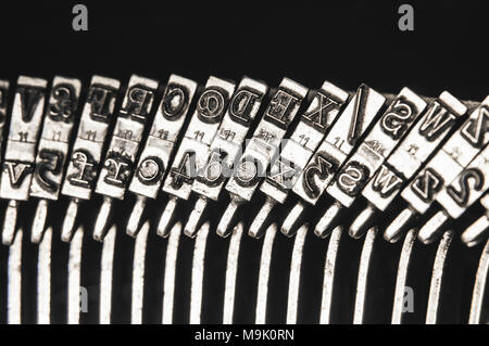 Close up di lettere, numeri e simboli di argento metallico tipo martelli da una vecchia macchina da scrivere meccanica. Filtrata in stile retrò. Foto Stock
