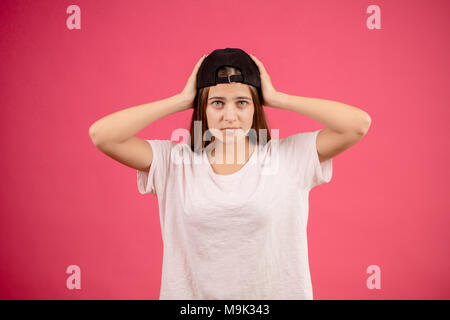 Close up ritratto di adolescente in abiti casual indossando il cappuccio nero isolato sullo sfondo rosa. tenere testa. Foto Stock