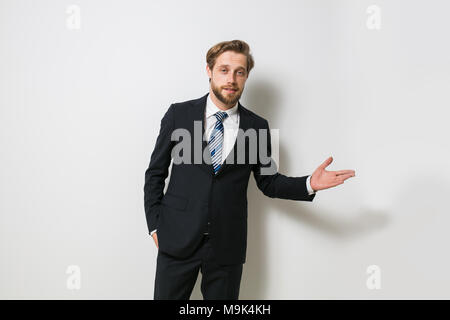 Fiducioso uomo pronto per concludere un business o un contratto, presentando uno dei lati o sia come una scelta, una bionda con barba in elegante costume Foto Stock