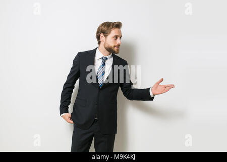 Fiducioso uomo pronto per concludere un business o un contratto, presentando uno dei lati o sia come una scelta, una bionda con barba in elegante costume Foto Stock