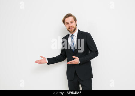 Fiducioso uomo pronto per concludere un business o un contratto, presentando uno dei lati o sia come una scelta, una bionda con barba in elegante costume Foto Stock