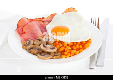 La prima colazione - Colazione Inglese di bacon, uova, funghi e fagioli al forno su una piastra e pronto da mangiare con la parola prima colazione. Foto Stock