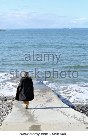 Una bella scena come una donna cammina per il scivolo verso la riva a Rosses Point sulla costa occidentale dell'Irlanda. Credito: reallifephotos / Alamy Foto Stock