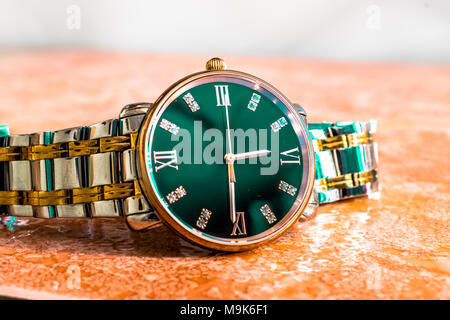 Un costoso ed elegante nuovo di zecca d'argento e d'oro uomo sottile dial watch mantenuta su un pavimento di marmo Foto Stock