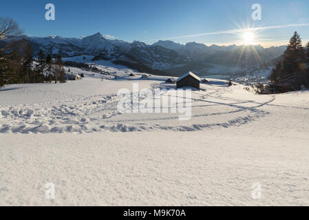 Montagna innevata prati da fieno capanne nella parte anteriore del panorama delle Alpi di Glarona al tramonto, Canton San Gallo, Svizzera Foto Stock