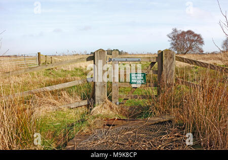 Una porta di accesso al terreno coltivato con accesso privato dal sentiero pubblico sulla Norfolk Broads a Horsey, Norfolk, Inghilterra, Regno Unito, Europa. Foto Stock