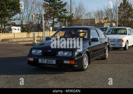 1986 nero Ford Sierra RS Cosworth benzina hatchback al North-West Supercar evento come auto e turisti arrivano nella località costiera. Le supercar degli anni '80 sono da paraurti a paraurti sulla spianata fronte mare, mentre gli appassionati di auto classiche e sportive amano trascorrere una giornata in auto. Foto Stock