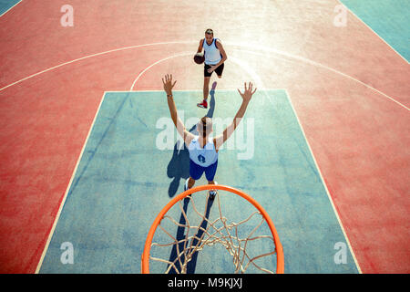 Angolo di alta vista del giocatore di basket dunking basket in hoop Foto Stock