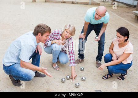 Allegro maschi e femmine giocando a bocce in th park nei giorni festivi Foto Stock