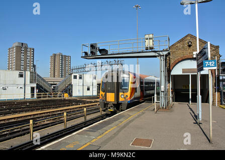 In treno arrivando a Clapham Junction station piattaforma. Foto Stock