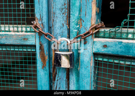 Un blocco di argento e la catena su una porta blu Foto Stock