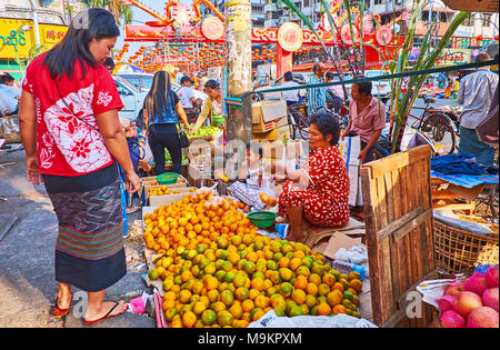 YANGON, MYANMAR - 14 febbraio 2018: Il mercato della frutta lungo il Maha Bandula Road, venditori ambulanti offrono arance fresche, di ananassi, di mele e altri, Foto Stock