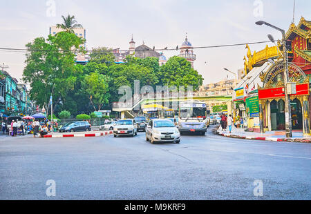 YANGON, MYANMAR - 14 febbraio 2018: il traffico sulla rotatoria stradale tra Sule Pagoda e Bengali moschea sunnita, visto dietro il verde, sul Fe Foto Stock