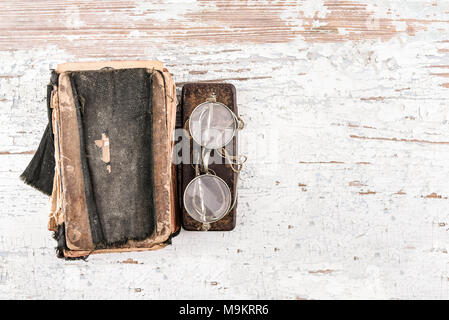 Antico libro di preghiera con gli occhiali rotondi 1920s e caso sul tavolo di legno, vista dall'alto, il luogo per il testo o gli elementi di design Foto Stock