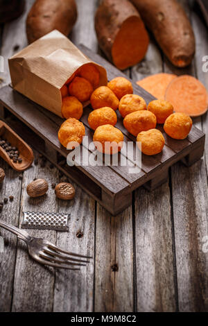 Dolci fatti in casa crocchette di patate in un sacchetto di carta su sfondo di legno Foto Stock