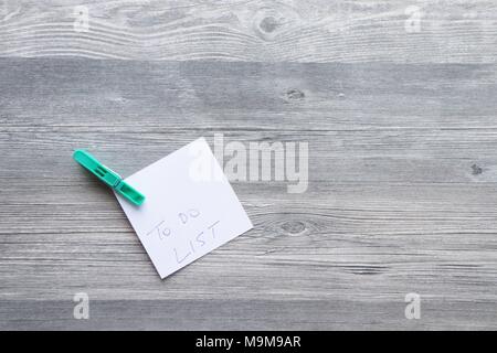 Note scritte a mano su carta bianca, vestiti colorati peg, grigio Sfondo plank, lo spazio per la copia Foto Stock