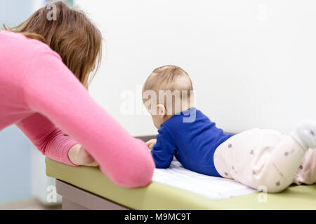 Bambino con sua madre giocando sulla modifica della tabella. Mom dando sonaglio giocattolo per baby boy. Vista da sopra Foto Stock