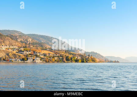 Case fronte mare e montagne sul lago con il cielo blu e calda luce dal sole serale in autunno Foto Stock