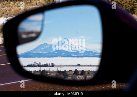 La cima innevata del Monte Shasta si eleva alto in un auto veduta laterale porta specchio nella California del Nord in inverno Foto Stock