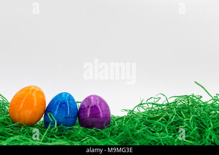 Fila di uova di Pasqua in fresco di erba verde con sfondo bianco Foto Stock