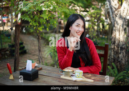 Ritratto di giovane e bella donna con caffè in giardino Foto Stock