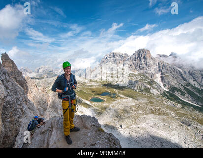 Escursionista sulla via ferrata alla Paternkofel, dietro il Lago dei Piani con Schusterplatte e Altensteinspitz, Dolomiti di Sesto Foto Stock
