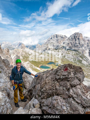 Escursionista sulla via ferrata alla Paternkofel, dietro il Lago dei Piani con Schusterplatte e Altensteinspitz, Dolomiti di Sesto Foto Stock