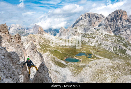 Escursionista sulla via ferrata alla Paternkofel, dietro il Lago dei Piani con Schusterplatte e Altensteinspitz, Dolomiti di Sesto Foto Stock