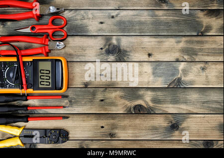 Close up degli strumenti di lavoro per il residenziale impianto elettrico su un vecchio tavolo di legno. Spazio per testo / annuncio. Foto Stock