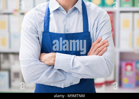 Shop assistant che pongono al supermercato con le braccia incrociate, lavoro retail concept, irriconoscibile persona Foto Stock