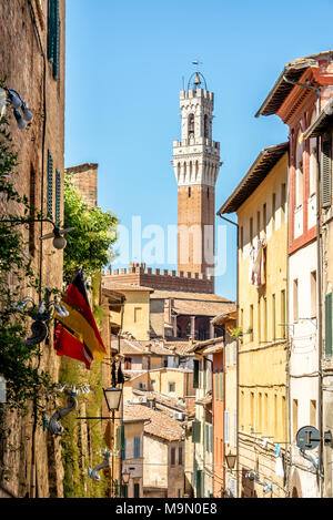 Strada stretta a Siena, vista sulla Torre del Mangia, Toscana, Italia Foto Stock