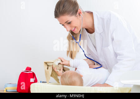 Pediatra dedicato utilizzando lo stetoscopio durante il check-up Foto Stock