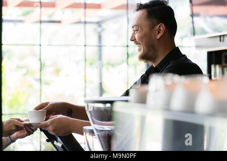 Cordiale Barista serve un espresso corto a un cliente Foto Stock