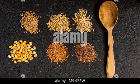 Pile di sei diversi grani su sfondo nero Foto Stock