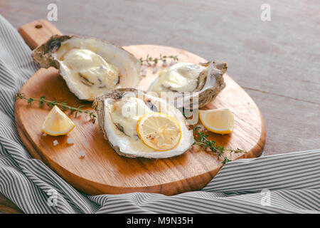 Ostriche fresche in guscio con limone sul bordo di taglio Foto Stock