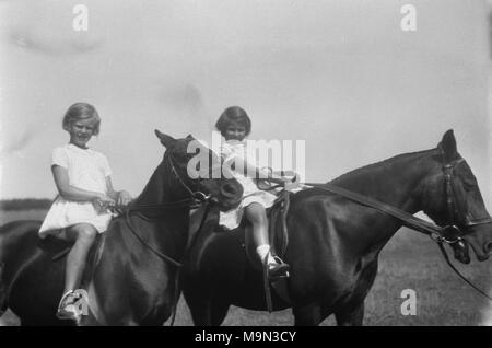 1920s, foto storiche, la vita rurale in Inghilterra, prima della data prevista di arrivo sulla massa dell'autovettura, molti giovani hanno imparato a cavalcare cavalli e qui possiamo vedere due giovani ragazze abiti da indossare comodamente seduti su due grandi cavalli. Foto Stock