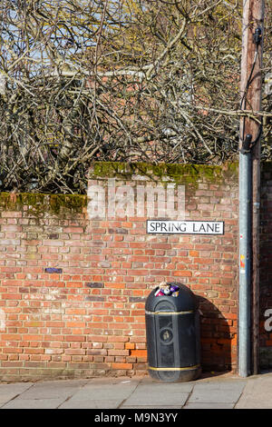 Un traboccante inferriata contro un rosso storico muro di mattoni all'entrata di Spring Lane, St Martin's Hill, Canterbury, Kent, Regno Unito Foto Stock