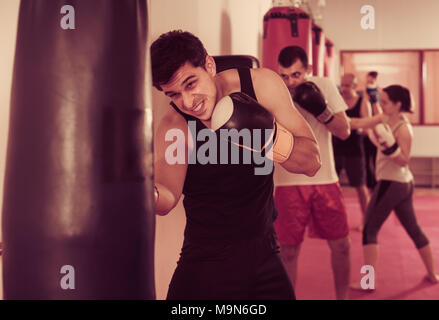 Strenui sportivo nella sala boxe Boxing praticanti punzoni con Sacco boxe durante il corso di formazione Foto Stock