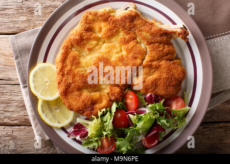 Vitello milanese (cotoletta alla milanese) con limone e una fresca insalata di verdure close-up su una piastra. parte superiore orizzontale vista da sopra Foto Stock