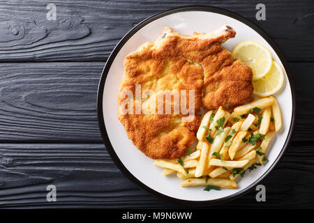 Tradizionale Italiana Milanese di vitello con limone e patatine fritte close-up su una piastra. parte superiore orizzontale vista da sopra Foto Stock