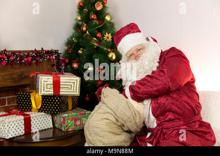 Buon Babbo Natale riceve un regalo da una grande borsa grigia - un giocattolo morbido. Foto Stock
