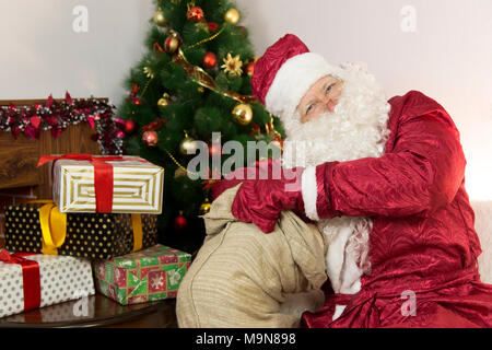 Buon Babbo Natale riceve un regalo da una grande borsa grigia - un giocattolo morbido. Foto Stock