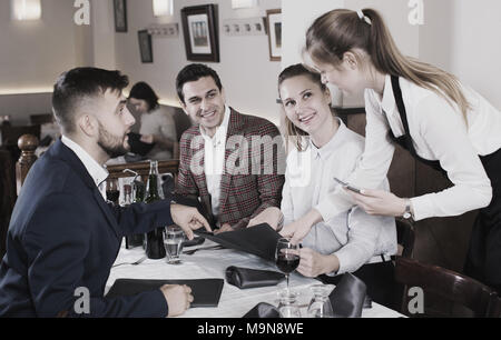 Sorridente cameriera facendo ordine da ospiti, usando tavoletta digitale Foto Stock