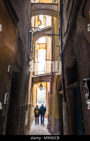 Due turisti senior giovane camminando per uno stretto vicolo buio in un italiano medievale città tradizionale Foto Stock