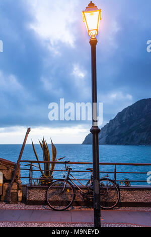 Via lampada lanterna accesa al tempo della sera illuminando un percorso panoramico con vista sul mare e sulla costa. Noleggio parcheggiato dietro di esso. Foto Stock