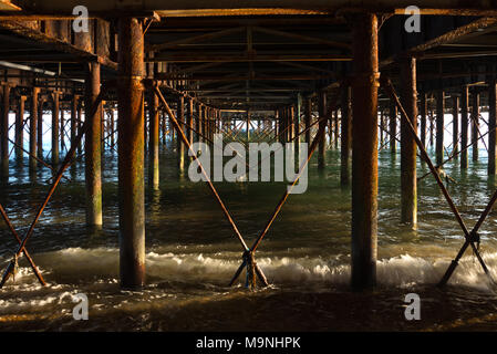 Vista lungo il lato inferiore della Portsmouths South Parade Pier a Southsea, Inghilterra, lato illuminato su una calma giorno mostra travi e pilastri Foto Stock