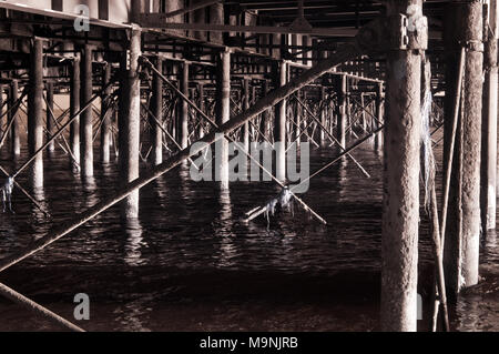 Vista a raggi infrarossi lungo il lato inferiore della Portsmouths South Parade Pier a Southsea, Inghilterra, lato illuminato su una calma giorno mostra travi e pilastri Foto Stock