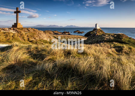 Queen Victoria Memorial Cross e il faro Twr Mawr sull'isola di Llanddwyn al tramonto, Anglesey, Galles del Nord, Regno Unito Primavera 2017 Foto Stock