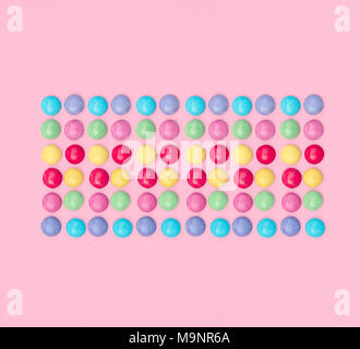 Un assortimento di caramelle colorate su sfondo rosa. Foto Stock